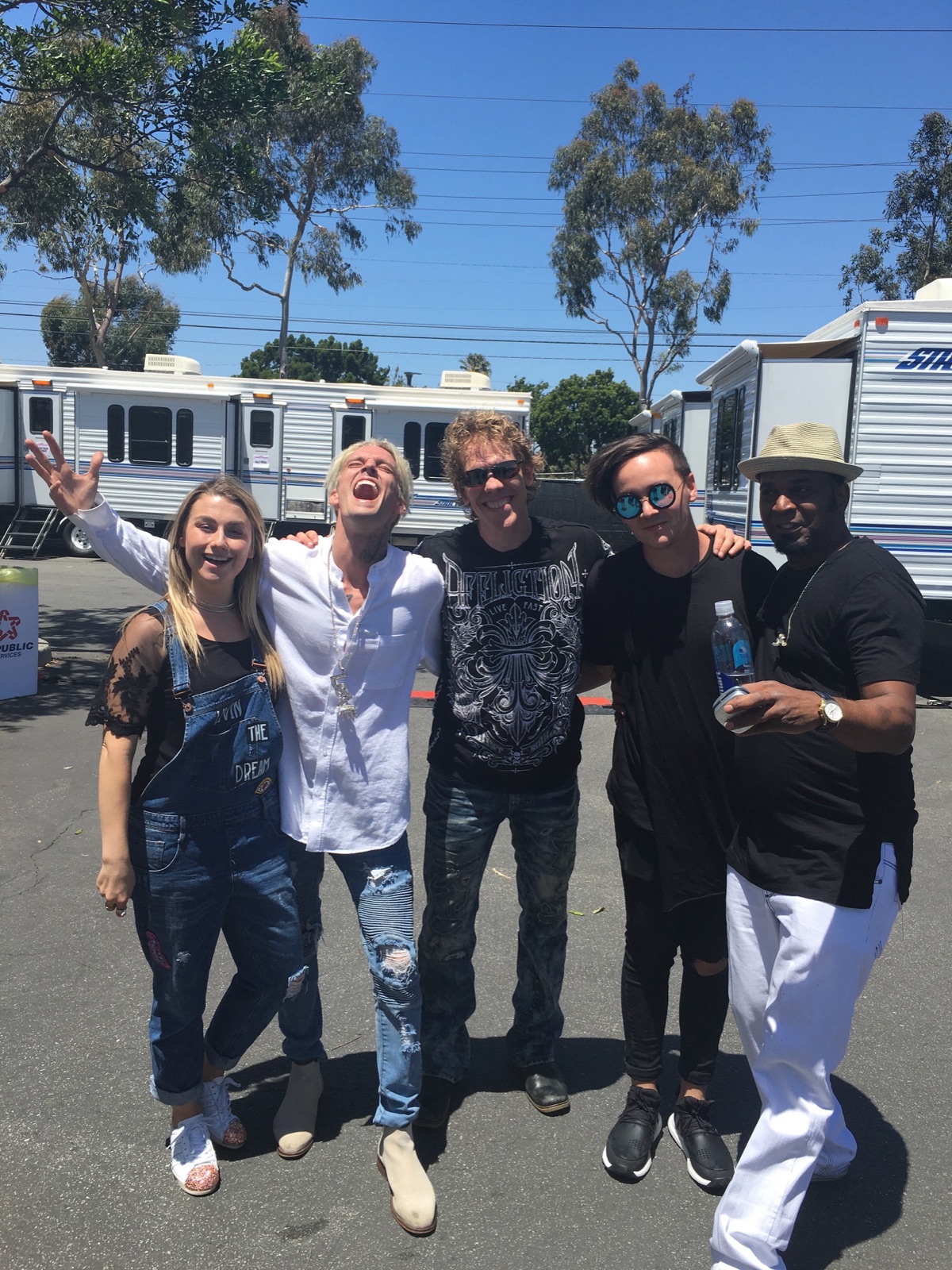 Erik backstage with Aaron Carter and the band, trailers and blue sky behind, everyone laughing