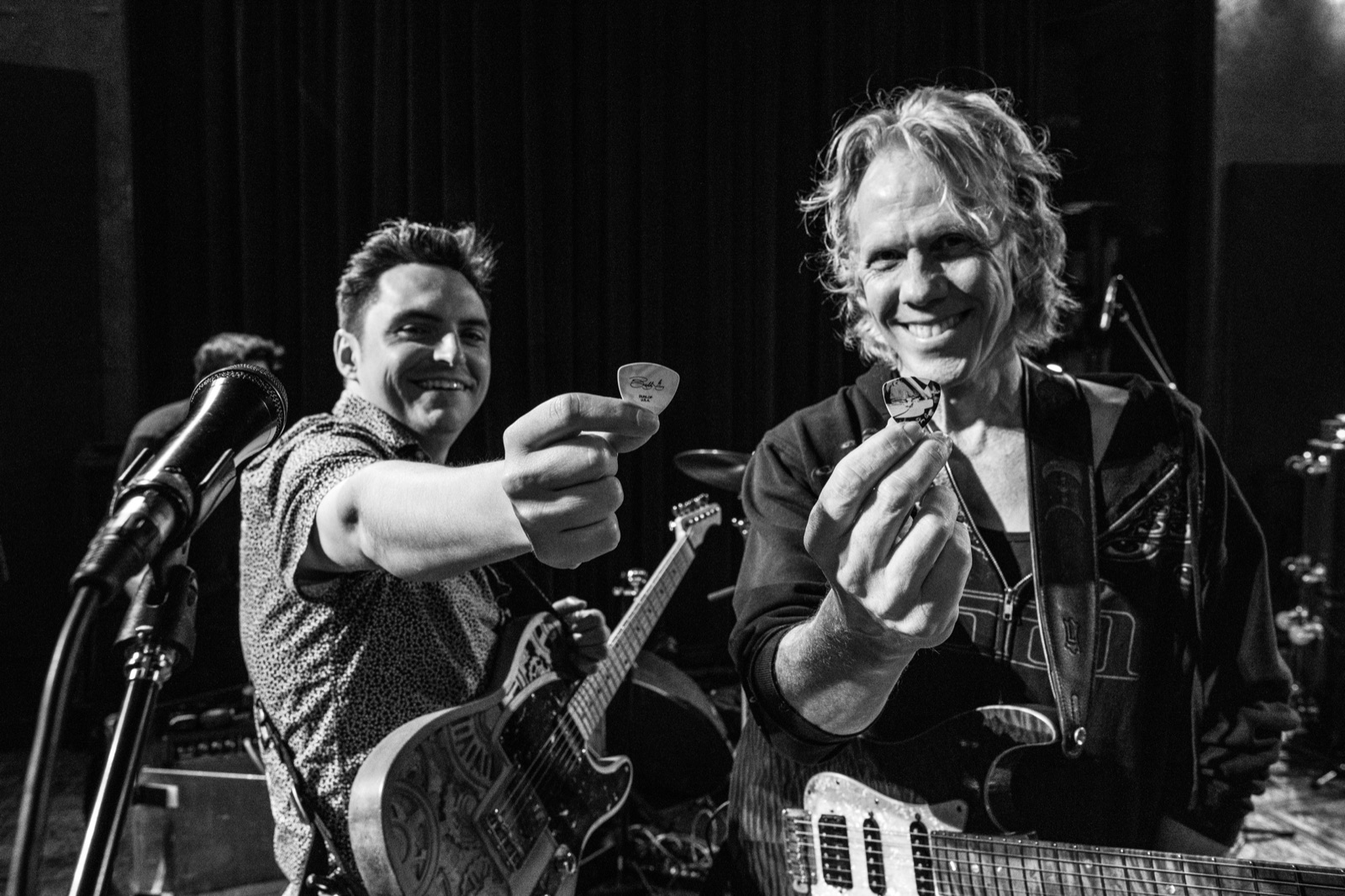 Black and white theater shot of Curtis Salgado pointing at the guitarists on stage